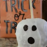 Apple decorated to look like a ghost with a trick or treat bag behind it and the words 