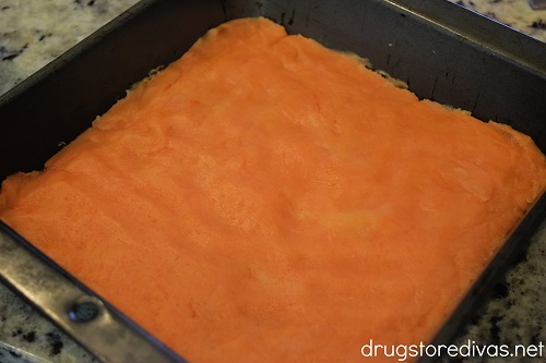 Orange cookie dough in an 8x8 pan.