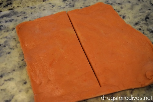 Square of orange cookie dough cut in half.
