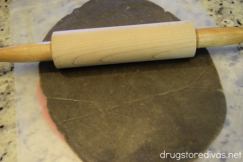 Rolling pin on top of black cookie dough.