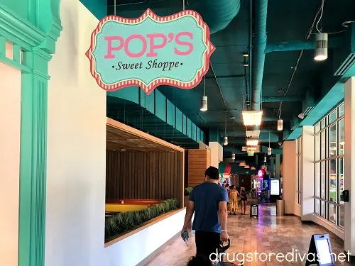 Man walking in a hallway under a sign that says "Pop's Sweet Shoppe."