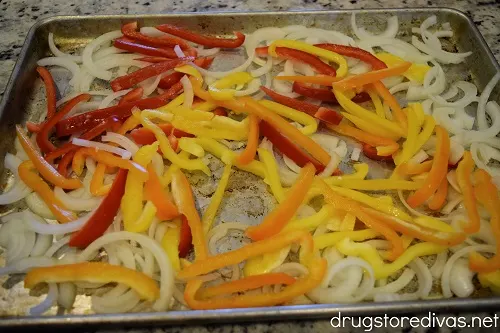 Sliced onions and peppers on a sheet pan.