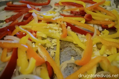 Sliced onions, peppers, and garlic on a sheet pan.