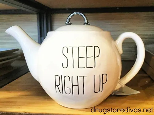 A white tea kettle that says Steep Right Up on it.