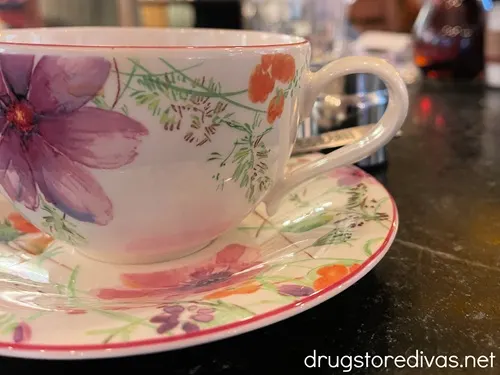 A white cup and sauce decorated with flowers.