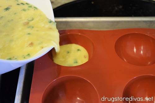 Egg mixture pouring from a bowl into a silicone baking mold.
