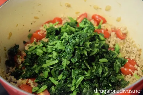 Kale, tomato, and ground sausage in a Dutch oven.