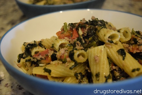 Sausage pasta with kale and tomatoes in a bowl.