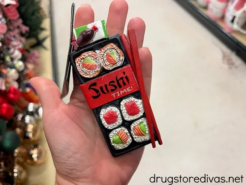 A hand holding a sushi tray Christmas ornament.