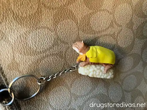 A keychain that looks like a cat-shaped piece of sushi attached to a Coach purse.