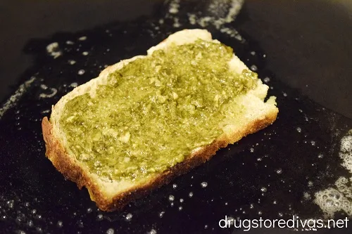 Piece of bread with pesto on it in a pan.
