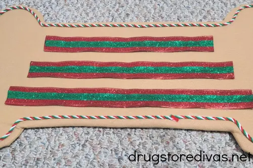 Red, white and green twisted cord around the edge of a brown felt-wrapped bone, plus three rows of red and green ribbon in the center..