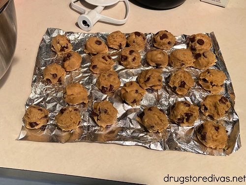26 balls of chocolate chip cookie dough on a piece of foil.