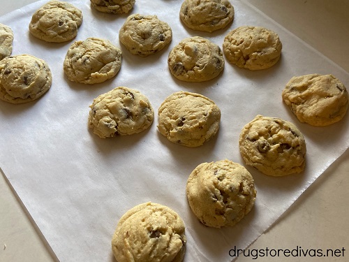 Baked chocolate chip cookies cooking on parchment paper.