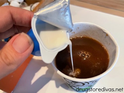 Creamer being poured into a cup of coffee.