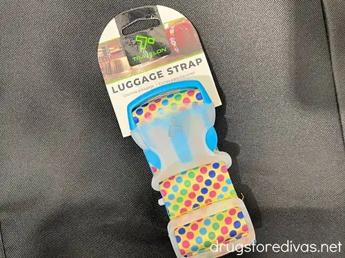 A colorful luggage strap in a package on a black background.