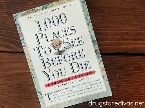 A book called "1,000 Places To See Before You Die" on a wooden table.