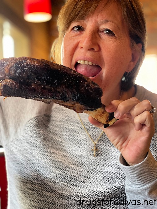 Woman eating a beef rib from Smokey Bones Bar & Fire Grill.