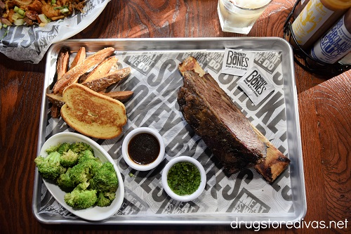 Beef rib, toast, fries, and broccoli on a tray with two sauces.