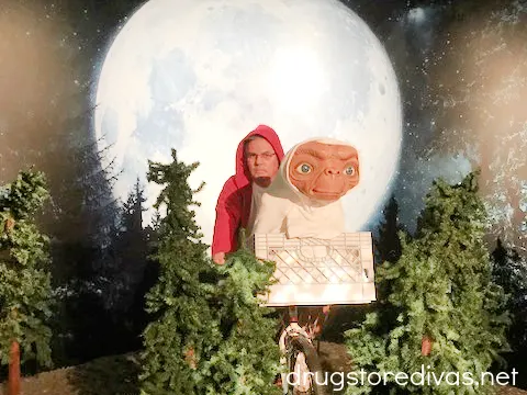A man posting with a wax ET in front of a moon at Madame Tussauds wax museum.