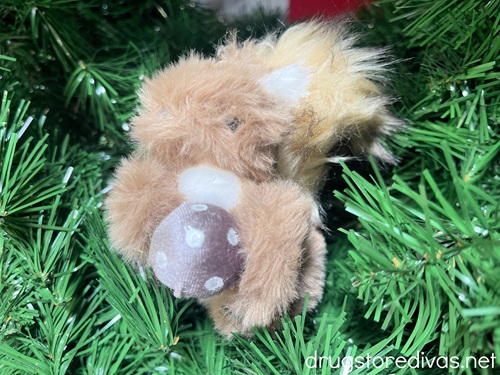 A squirrel Christmas ornament on a fake tree.