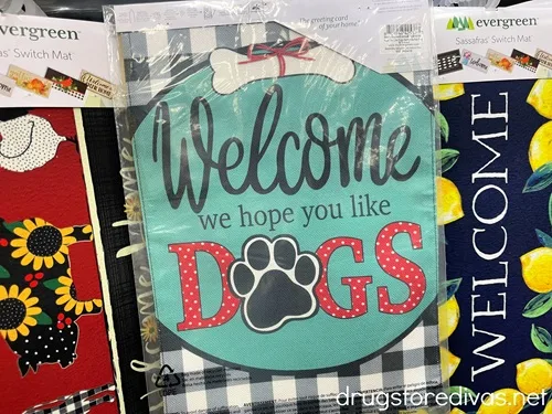A garden flag that says Welcome We Hope You Like Dogs on it.