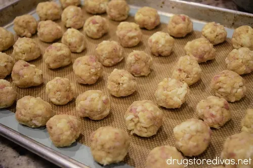 Scoops of cornbread sausage balls on a silicone baking mat-lined cookie sheet.