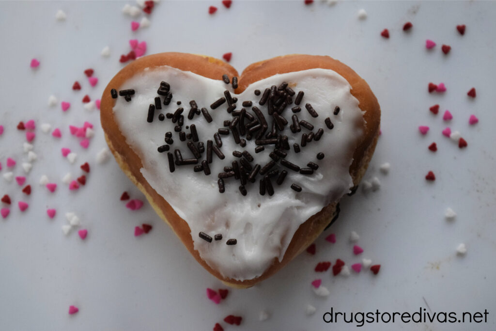 Heart-shaped donut surrounded by sprinkles.