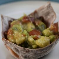 A guacamole cup on a plate with the words 