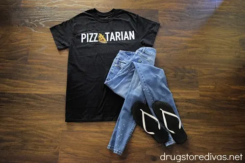 Shirt with the word pizzatarian on it, with jeans and black and white flip flops.