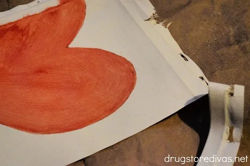 A piece of canvas, with a heart painted on it, being trimmed.