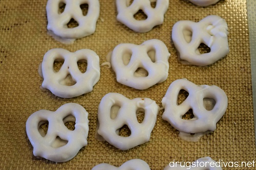 White chocolate covered pretzels on a baking mat.