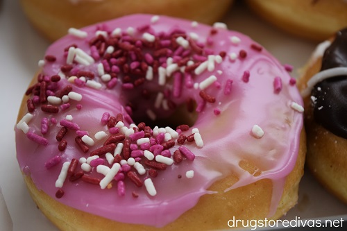 Donut with pink icing and red and pink sprinkles.
