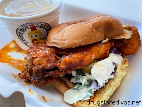 A fried cauliflower sandwich with a small container in the back from Dave's Hot Chicken.