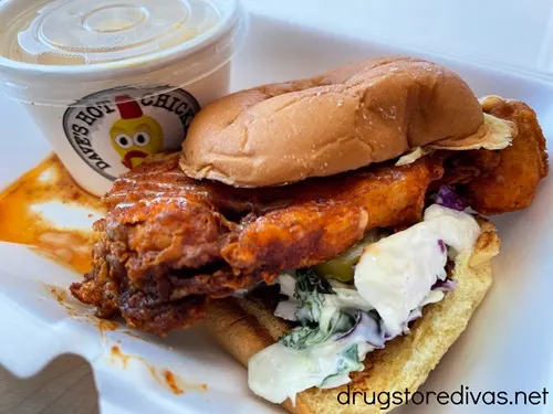 A fried cauliflower sandwich with a small container in the back from Dave's Hot Chicken.
