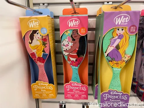 Three Disney Princess Wet Brushes hanging on pegs in a store.