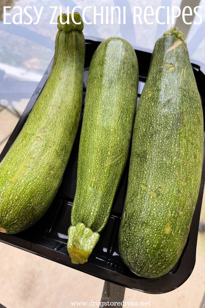 Three zucchini in a black container with the words "Easy Zucchini Recipes" digitally written on top.