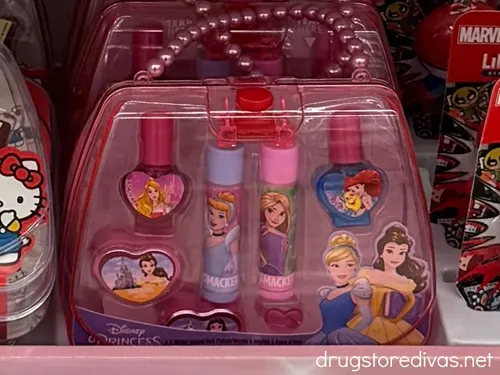 A pink plastic tote bag filled with Disney Princess makeup for kids.