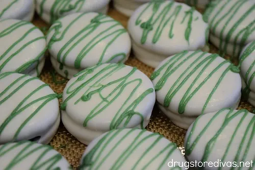 Green candy melts drizzled on white chocolate covered Oreo cookies.