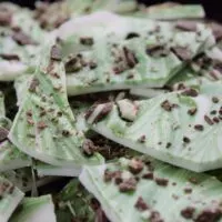 Pieces of green and white chocolate bark with mint chocolate pieces on top and the words 