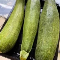 Three zucchini on a table with the words 