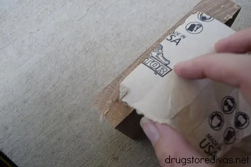 A wooden block being sanded with sand paper.