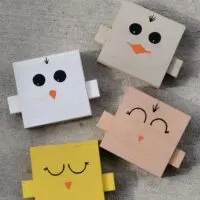 Four pieces of wood painted to look like chicken faces with the words 