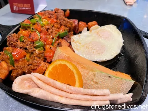 Chorizo hash, a fried egg, toast, a crepe, and an orange in a skillet from Hash House A Go Go In Las Vegas, NV.