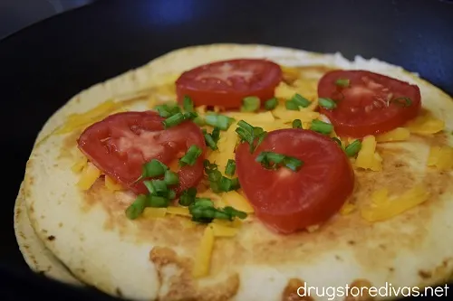 Tomatoes, green onion, and cheese on top of a pan.