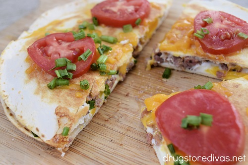 Four pieces of a Sausage And Egg Breakfast Quesadilla on a cutting board.