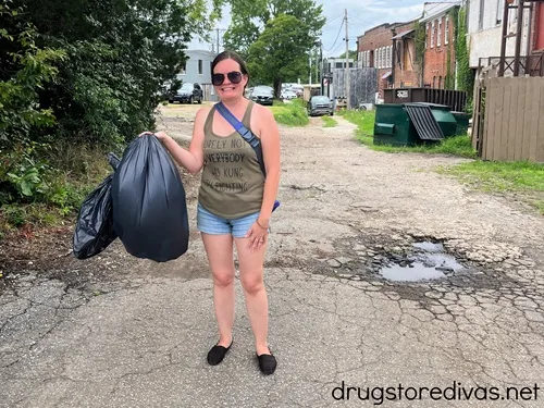 A woman carrying a black trash bag.