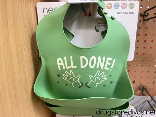 A green baby bib that says all done on a shelf in a store.