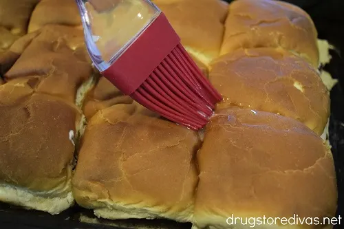 A pastry brush on top of Hawaiian rolls.