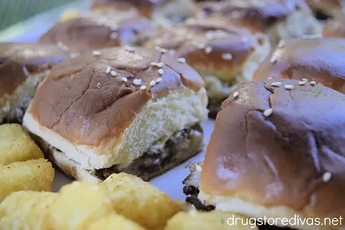 Cheeseburger sliders and tater tots on a pan.